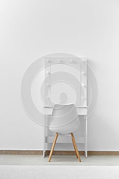 White makeup dressing table with lamps and a chair against a white wall