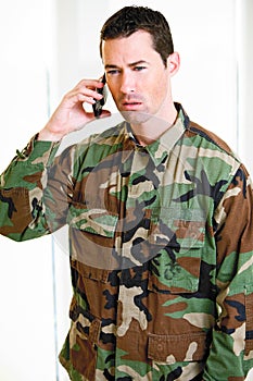 White male in army uniform on cell phone