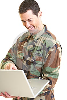 White male in army uniform on lap top smiling