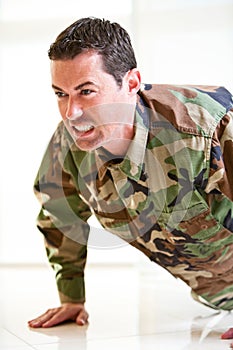 White male in army uniform straining doing a push up photo