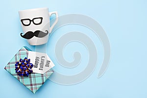 White male cup and gift box on blue background with copy space, father`s day present