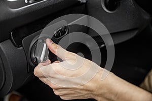 White male hand toggles headlight switch inside the black car