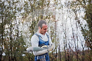 White man builder working with circular saw outdoors, portrait