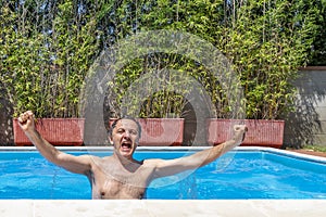 White man exults as if he has scored a goal inside a swimming pool photo