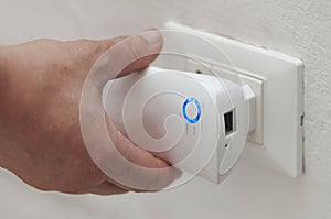 White man insert a wifi repeater in a wall plug photo