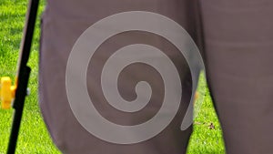 white man in plastic slippers moving green lawn with cheap plastic electrical lawn mover at sunny day, closeup