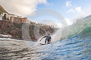 White man riding beach waves against the bright sky