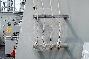 White Manila ropes or Nautical ropes with snap-link tied to the metal bar on the deck of warship