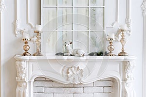 White mantelpiece with candles and christmas decorations. Classic interior.