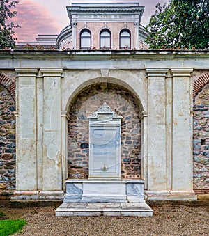 White marble drinking fountain in Mecidiye Pavilion garden, Istanbul, Turkey, with the palace in background