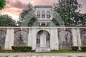 White marble drinking fountain mediating a stone brick fence revealing the Mecidiye Pavilion, Istanbul, Turkey