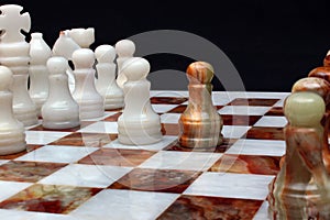 White marble and onyx stone chessboard with pieces on black back