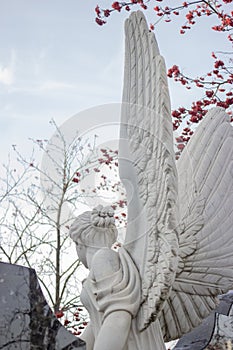 White marble sculpture against the sky and rowan branches with red berries