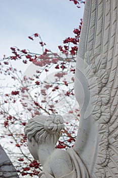 White marble sculpture against the sky and rowan branches with red berries