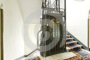 White marble stair area with carpets of a vintage building with the original restored elevator