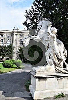 White marble statue of man holding a fiery horse in Vienna, in the center of the garden in the museum district.