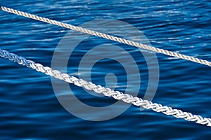 White marine mooring rope against background of blue water of Black Sea. Two white nautical cord. Background image