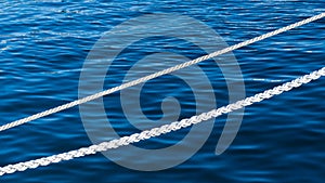 White marine mooring rope against background of blue water of Black Sea. Two white nautical cord. Background image