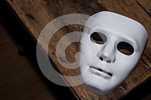 The white mask threatens on wooden table, killer concept, Halloween concepts