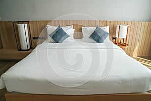 White mattress on minimal double bed with long big lamps at bedside in hotel bedroom