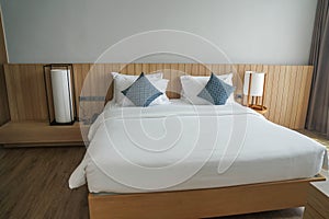 White mattress on minimal double bed with long big lamps at bedside in hotel bedroom