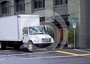 White mddle size delivery semi truck with box trailer on city st