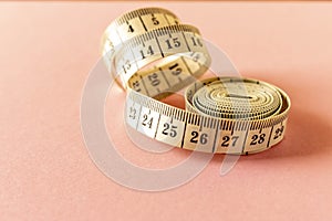 White measuring tape on a pink background. Close-up