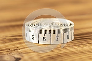 White measuring tape on a wooden background. Close-up