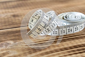 White measuring tape on a wooden background. Close-up