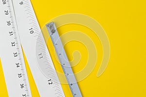 White measuring tapes with centimetre and inches on vivid yellow