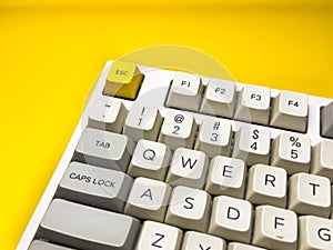 White mechanical keyboard with bright Esc key on bright yellow background,