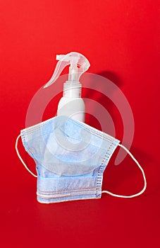 White medcine mask and bottle of desinfection on a red background
