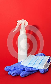 White medcine mask, gloves and bottle of desinfection on a red background photo