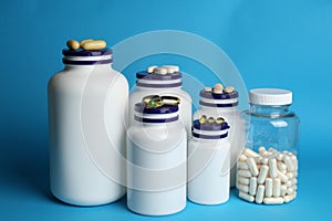 White medical bottles and different pills on light blue background