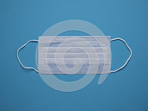 White medical face mask isolated on a blue background close up