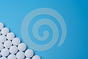 White medical pills on a blue background in the lower left corner.