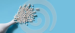 White medical pills and capsules or vitamines on blue background. Copy space. photo