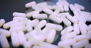 White medical pills fall on transparent glass and cover it.