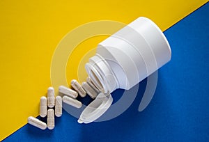 Medical pills with pill box on yellow and blue background