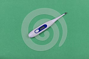 White medical thermometer on a green background