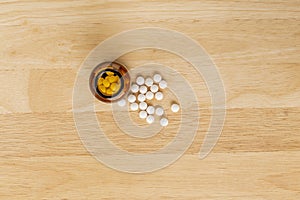 White medicinal antibiotics and glass bottle on a wooden background