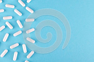 White medicine capsules on blue background with copy space