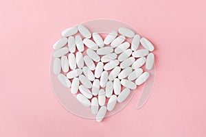 White medicine capsules on pink background.