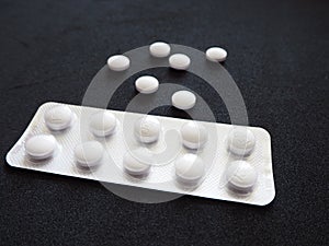 White medicine pills on a black background