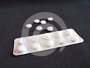 White medicine pills on a black background, modern medicine used to prevent and treat diseases with copy space