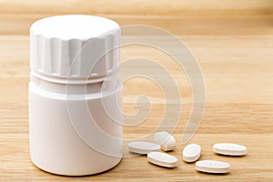 White medicine pills bottle on wooden table