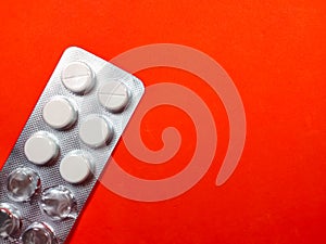 A white medicine pills on red background.