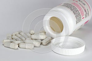 White medicine tablet antibiotic pills spilling out of a bottle, jar on white background