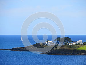 White Mediterranean-style houses with passing yacht against a blue sea at Chapel Point Cornwall