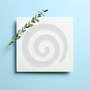 White memo pad, empty paper with eucalyptus leaves on sky blue background